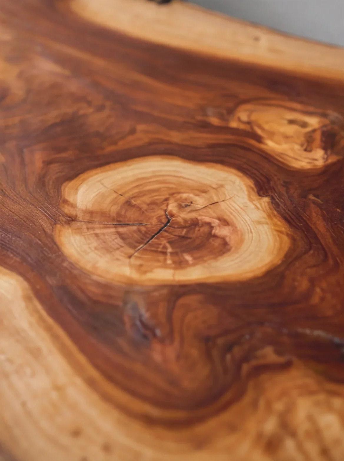 Close-up of live edge solid wood tabletop with natural grain patterns and warm tones