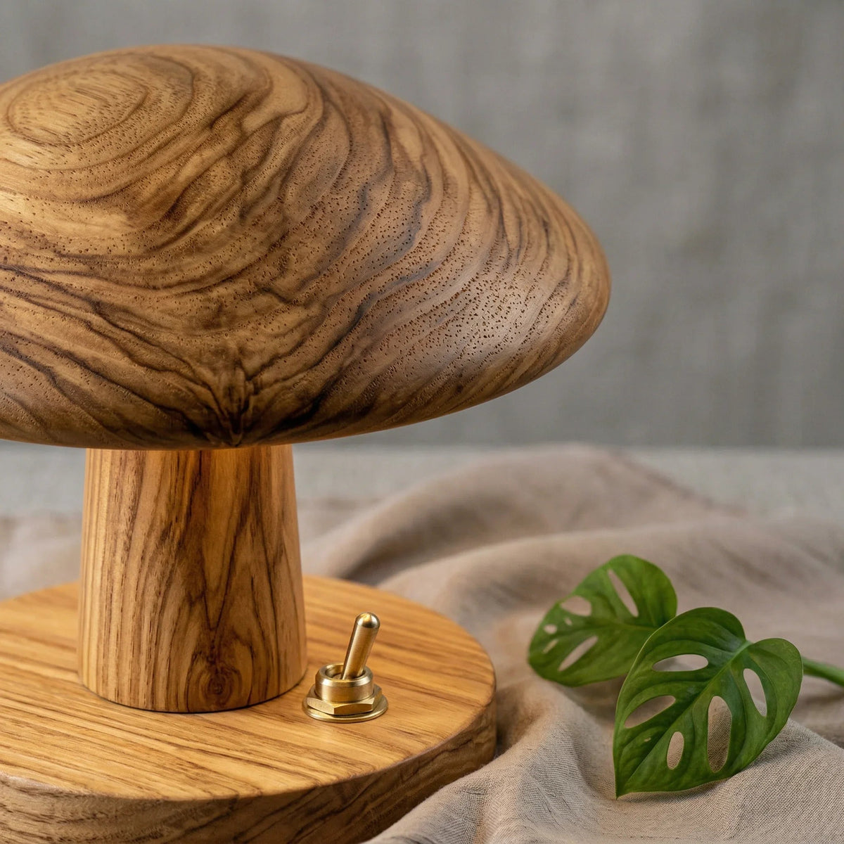 Closeup of a solid wood mushroom table lamp with natural grain, brass switch, and leaf decor