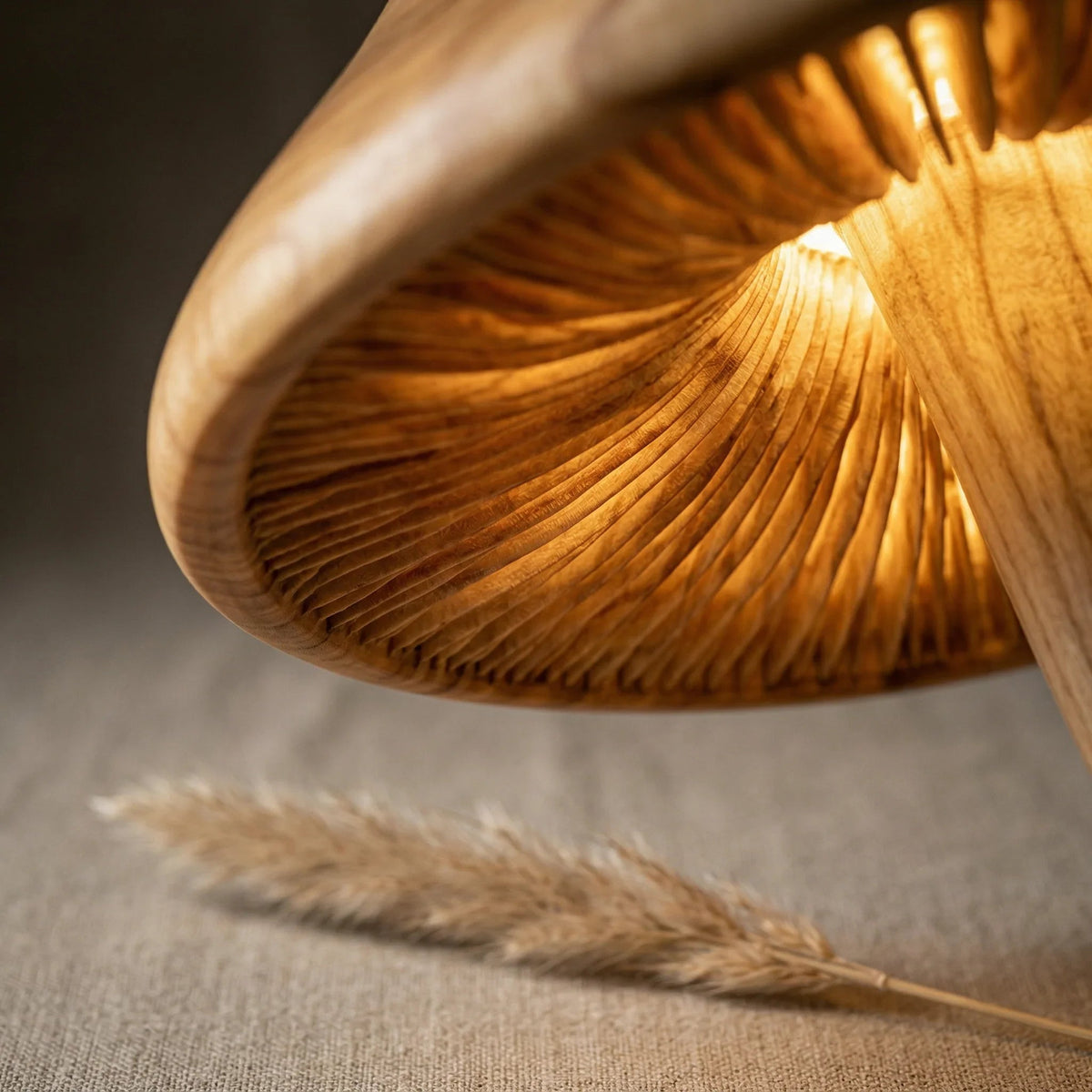 Close-up of illuminated hand-carved wood mushroom lamp cap with natural gill pattern.