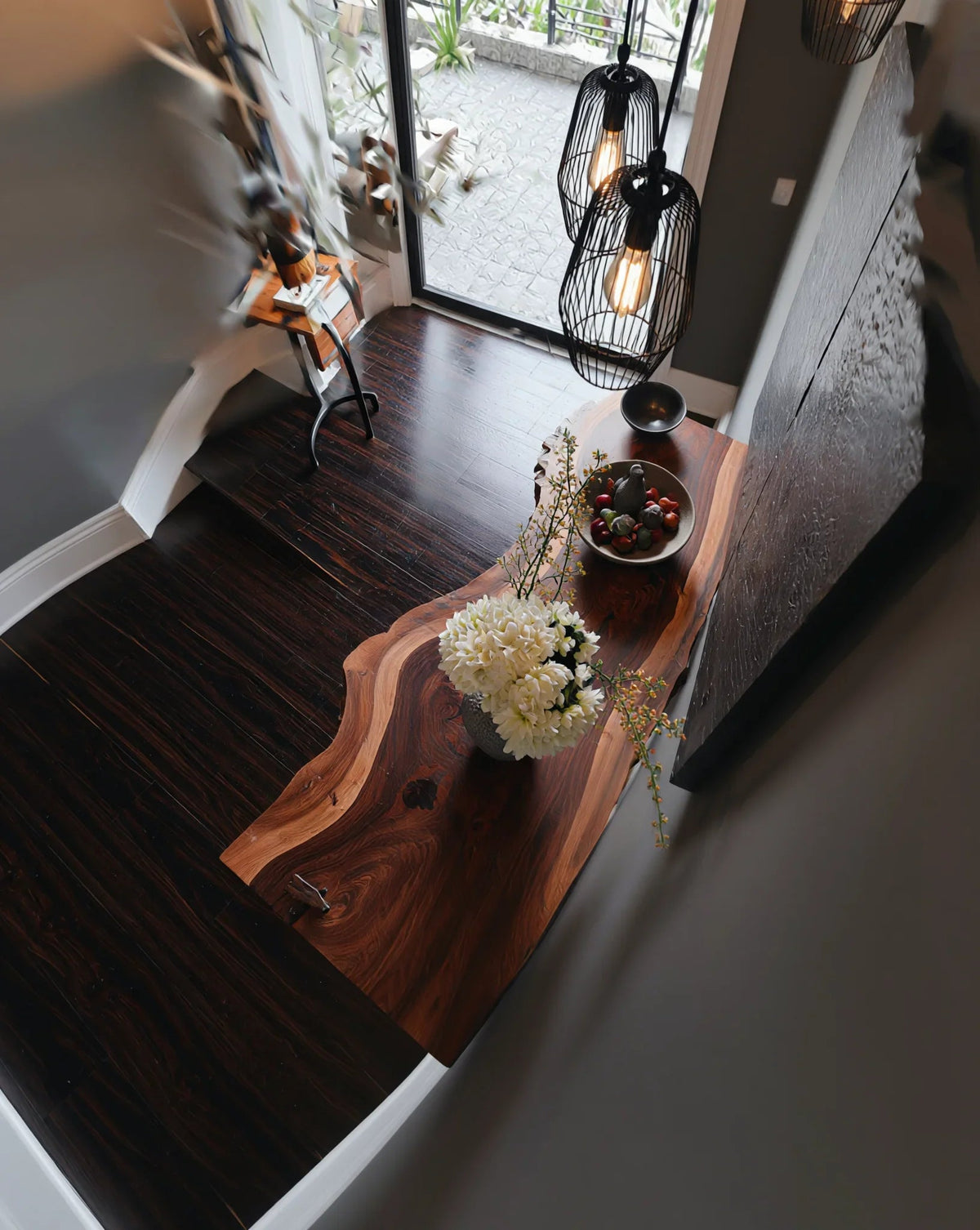 Live edge solid wood console table in modern entryway with floral decor and natural lighting