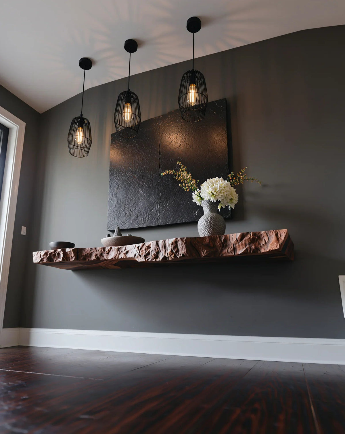 Live edge floating wood shelf with modern decor and pendant lights in a stylish room