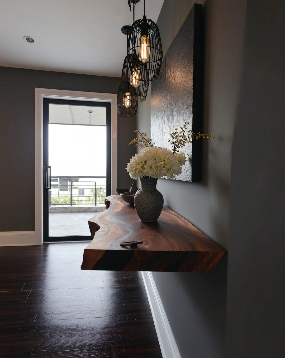 Live edge solid wood floating shelf in modern hallway with dark pendant lights and vase decor